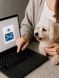 Person at a laptop with a dog beside them, sending a message